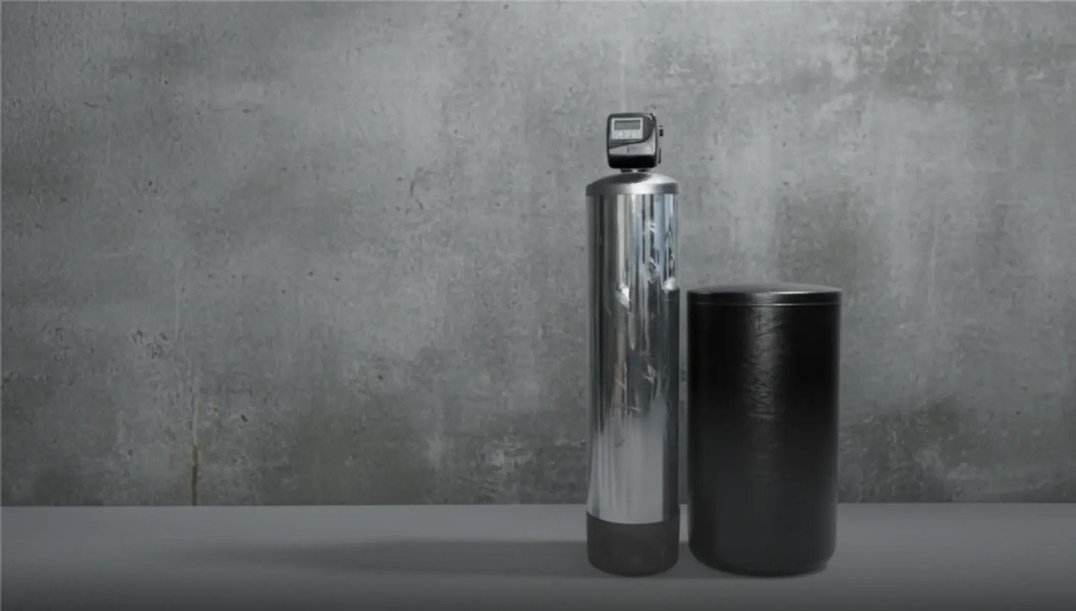 A home water treatment filtration system featuring a stainless steel conditioning tank and a black water softener brine tank.