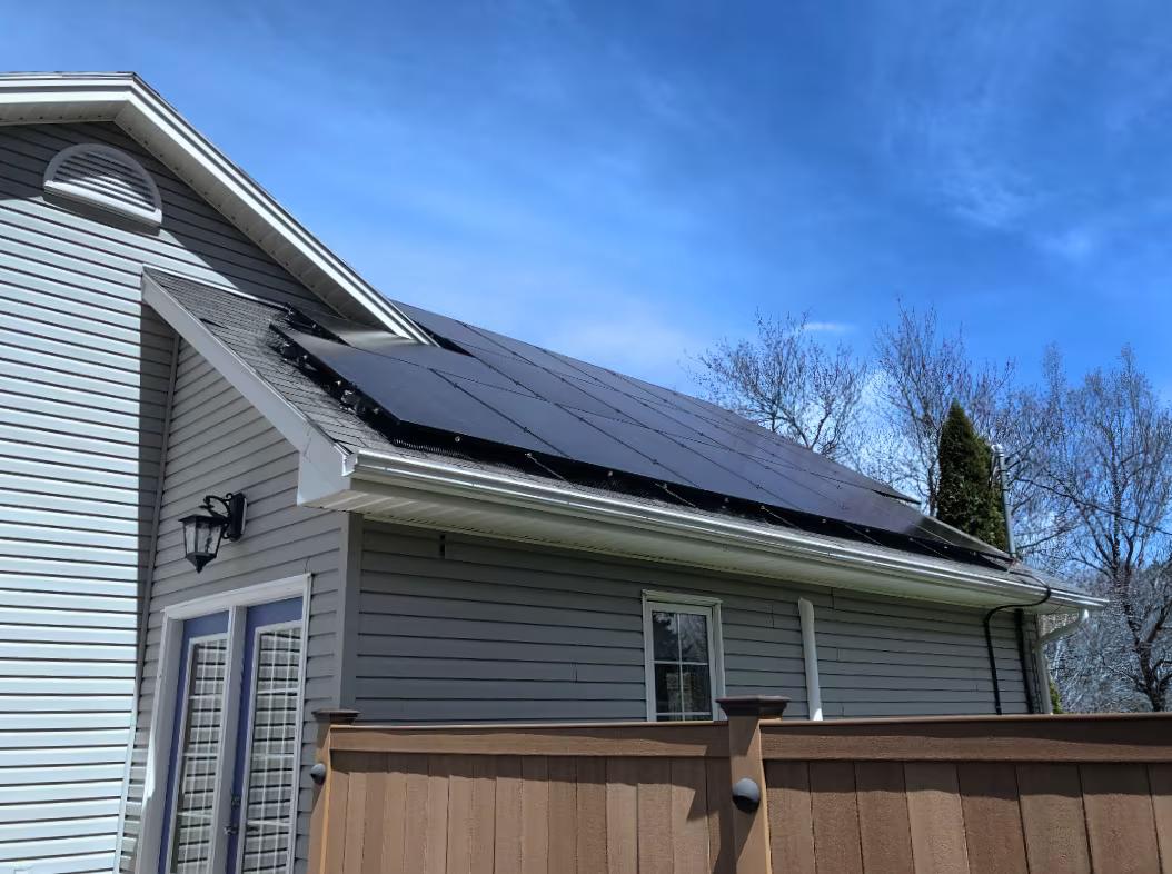 Residential solar energy project on rooftop of a white house with blue sky