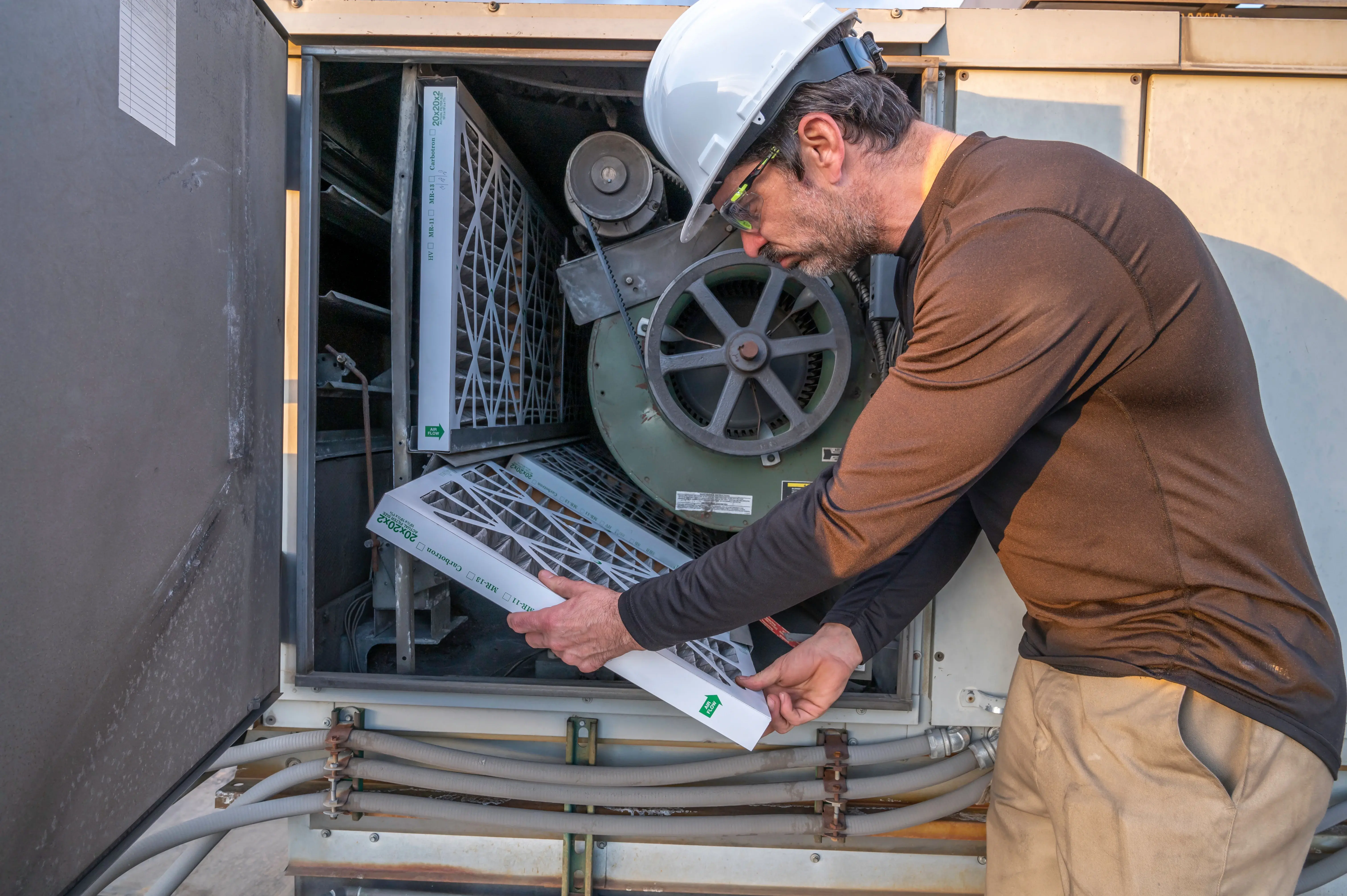 A technician is changing a filter of an HVAC system.