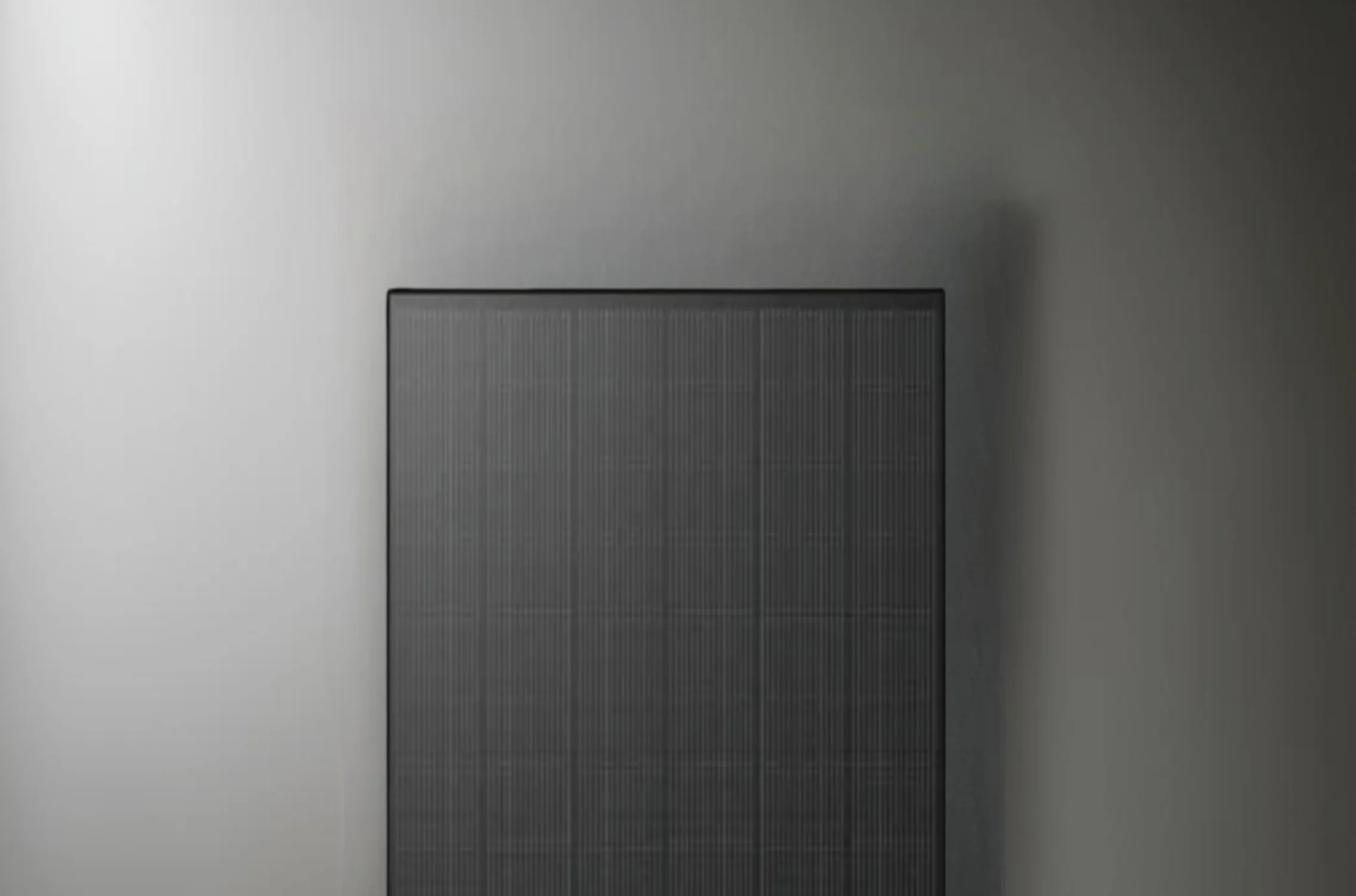 A square  Longi solar panel lying on the gray wall.
