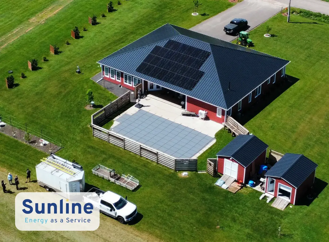 An aerial drone view of a large rural residential home featuring a dark rooftop solar panel array, optimized for the Sunline Energy as a Service flexible financing program.